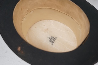 A gentleman’s black silk top hat with a black felt band and, cream silk lining, together with a brown leather case, hat height 17cm. Condition - silk brim worn in various places, leather case very poor